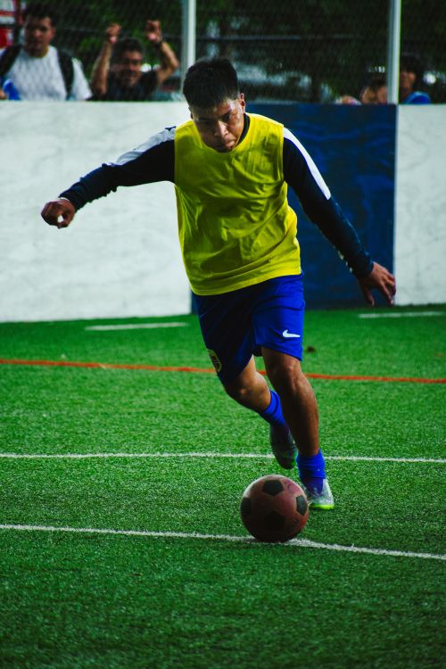 Free A young football player dribbles the ball on a field in Mexico City. Stock Photo