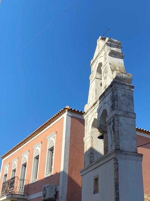 Free A striking bell tower stands against a bright blue sky in a Greek village. Stock Photo