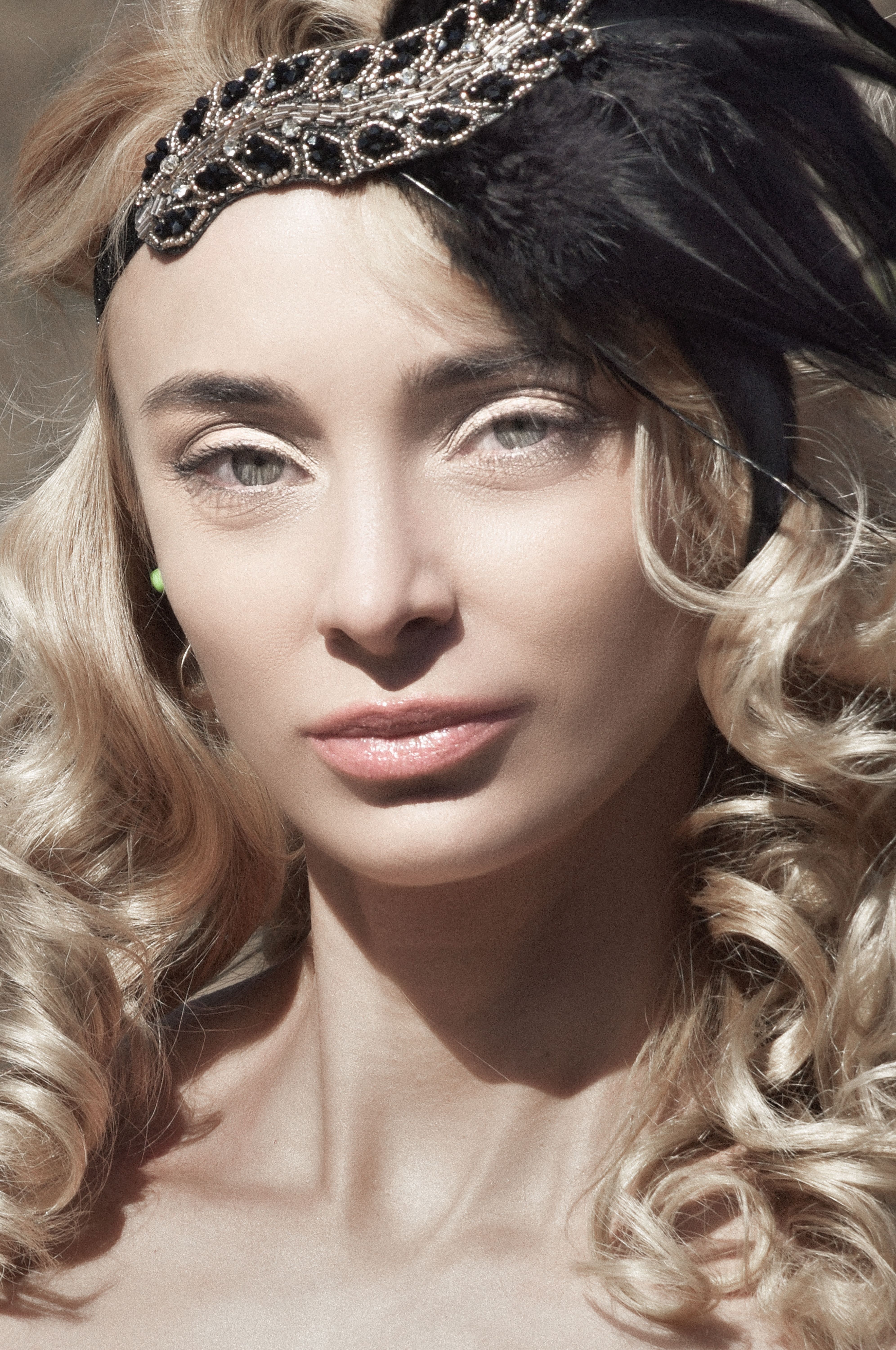 Close-up of woman wearing vintage headband with feathers and curls.