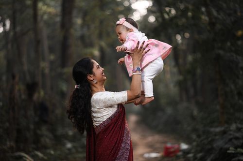 Free A mother joyfully lifts her baby in a serene forest, capturing a tender moment of love. Stock Photo