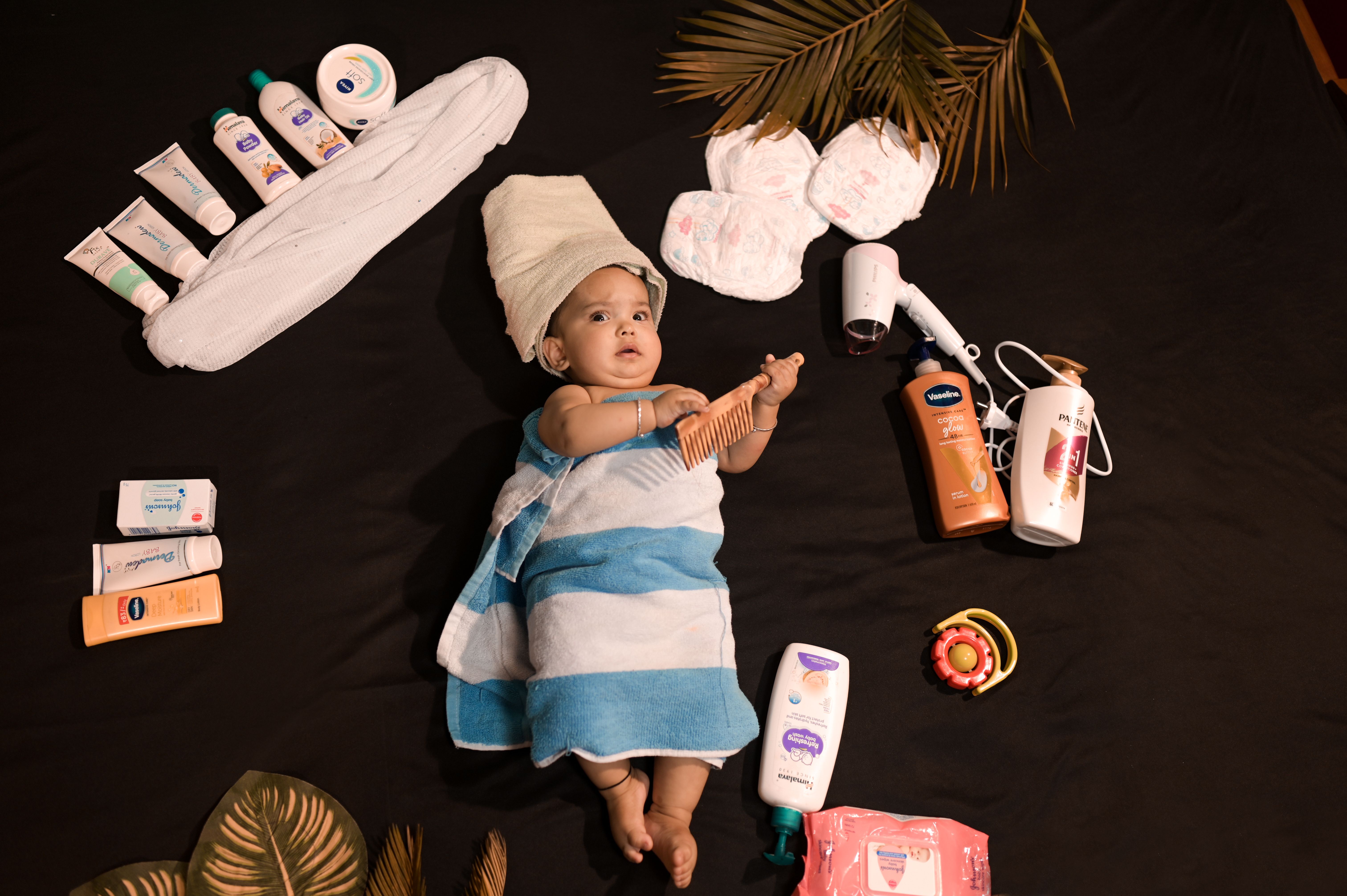 Adorable baby wrapped in towel with skincare essentials. Perfect for beauty and childcare themes.