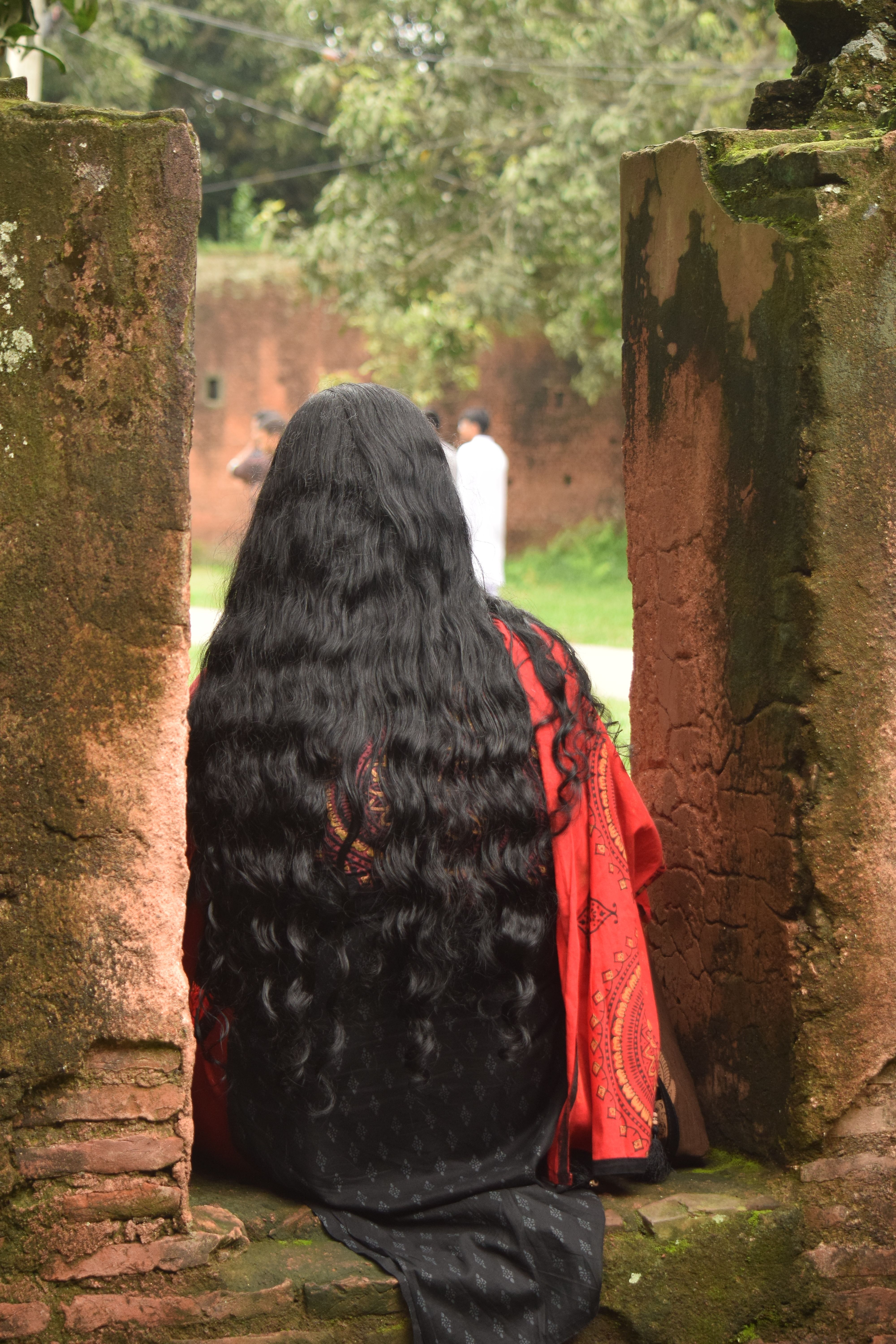 Rear view of a woman in traditional attire at Sonargaon's historic architecture.
