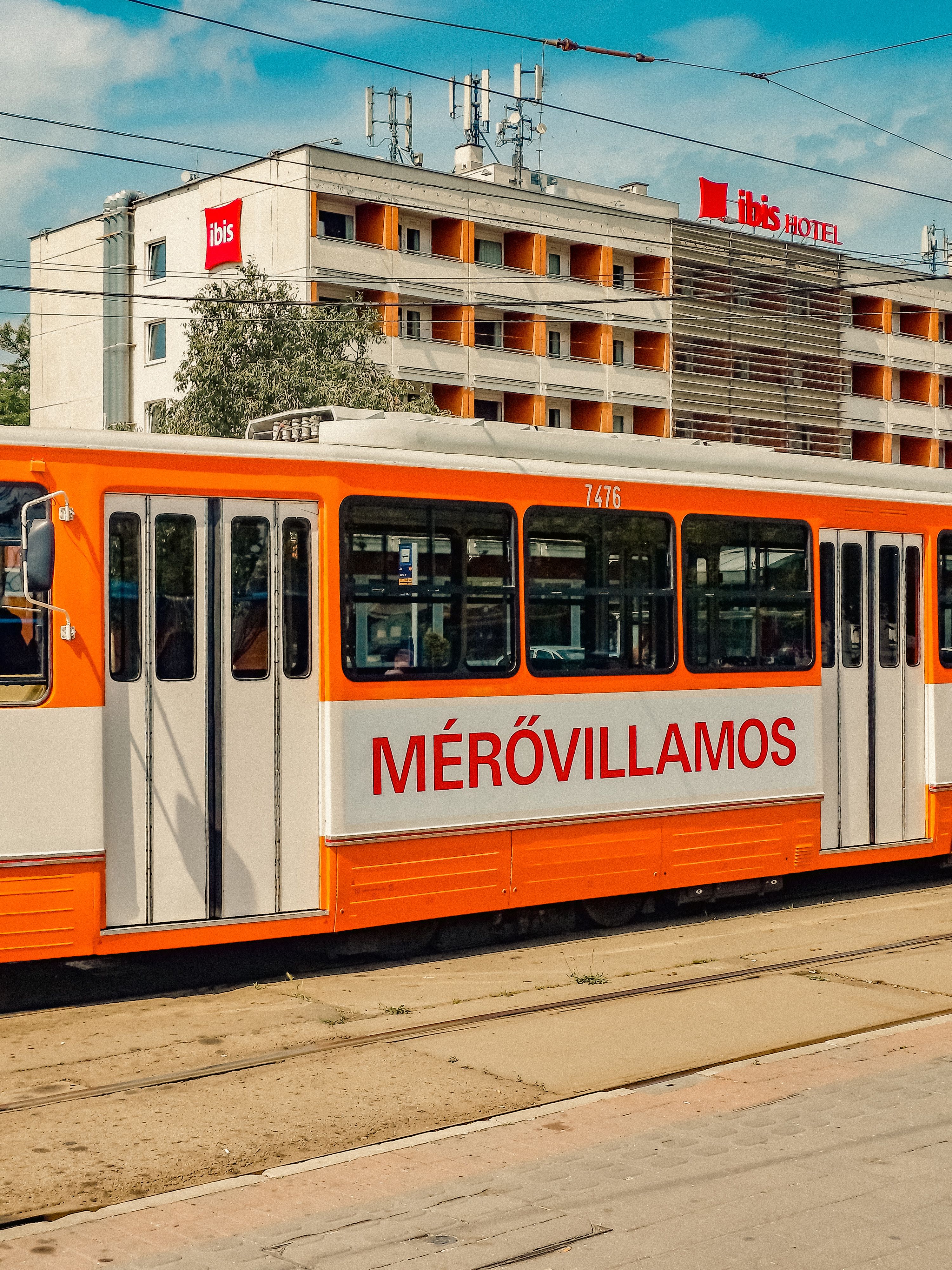 A vibrant tram passes an Ibis Hotel in Budapest, Hungary. Sunny day.