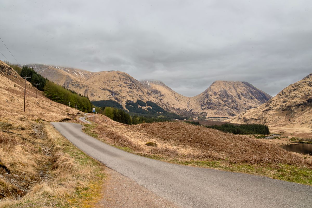A single track road winding through Glen Etive with mountains around
