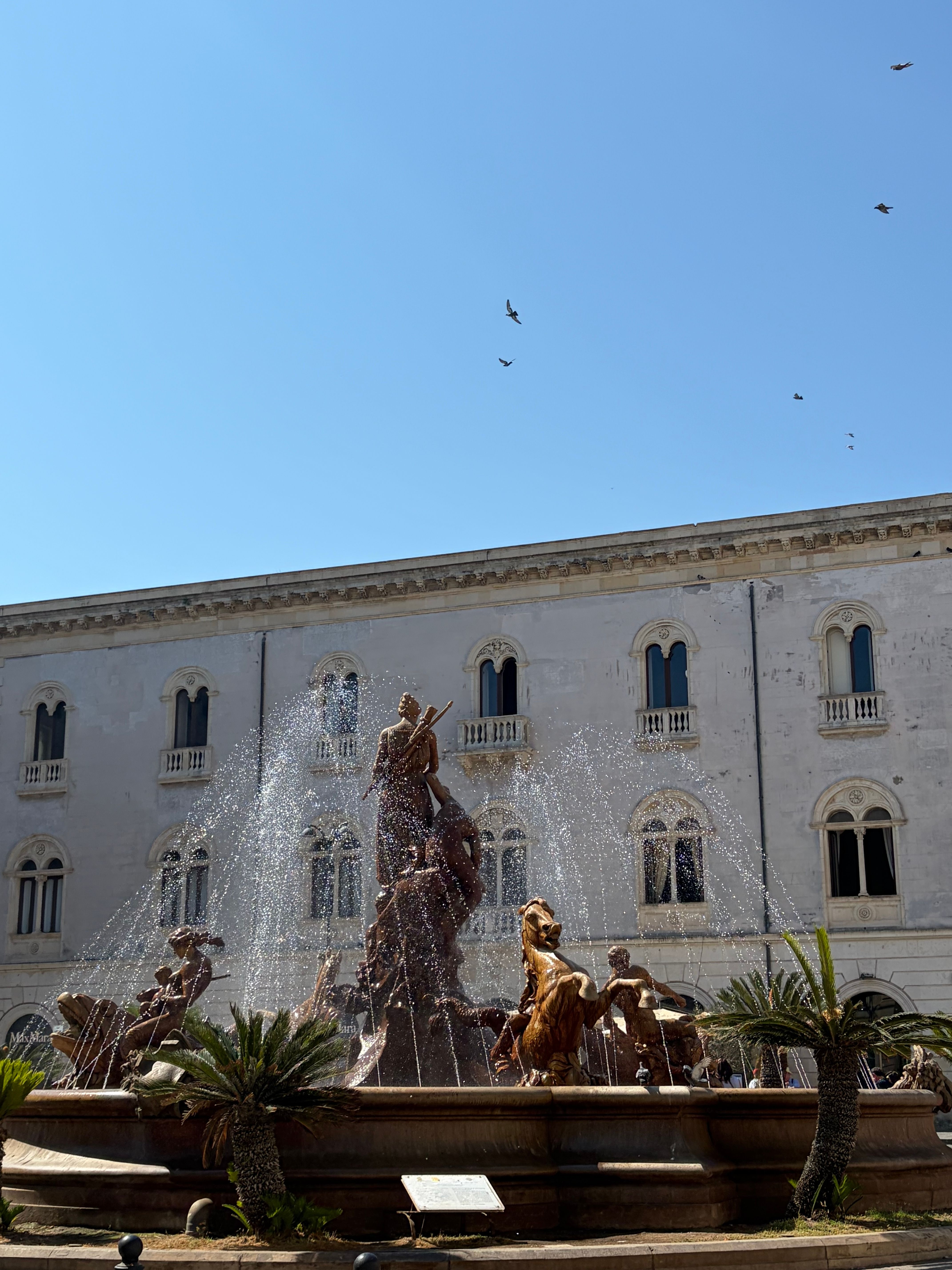 Stunning view of the Fountain of Diana in Piazza Archimede, Syracuse, Italy under a clear blue sky.