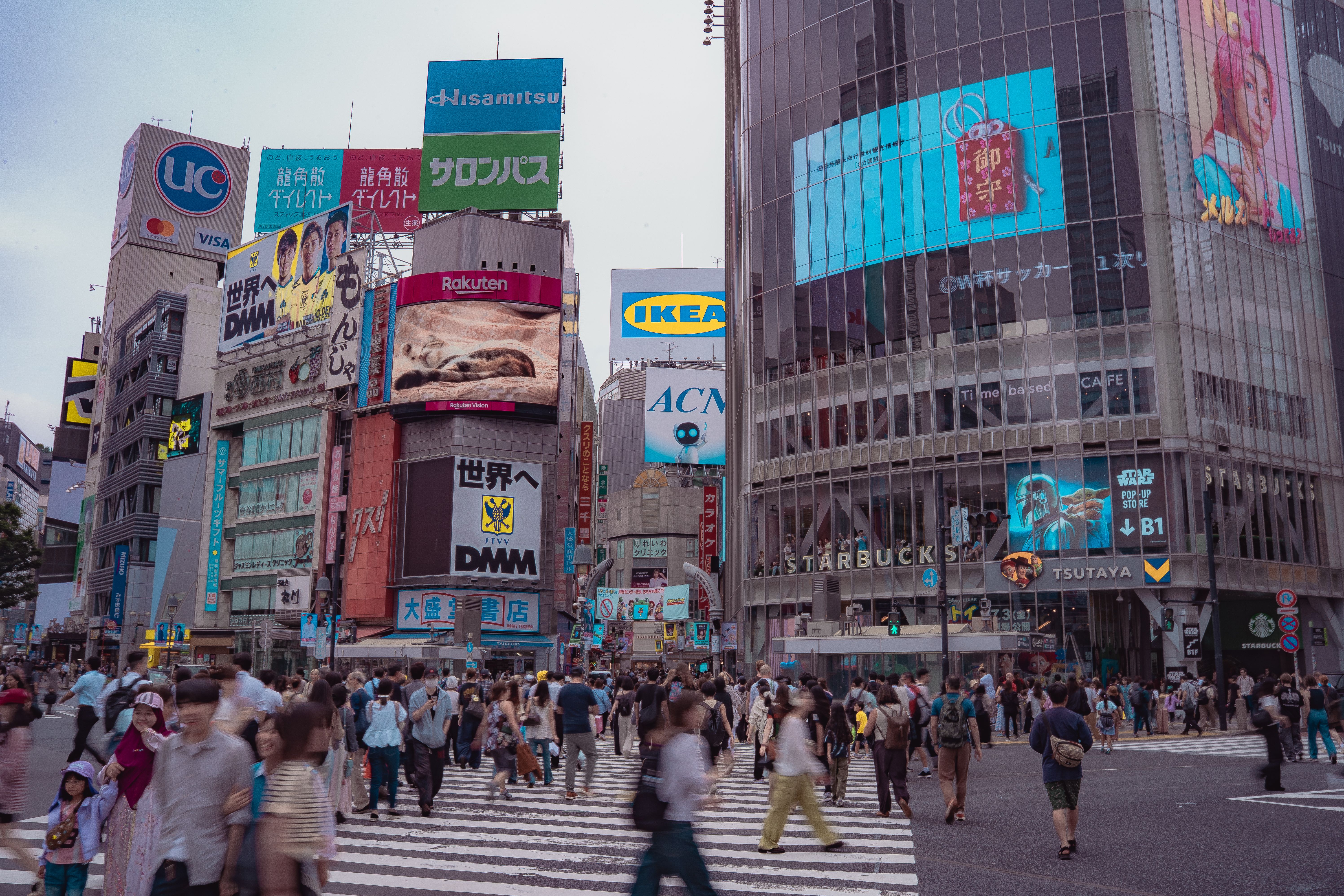 Crowds cross the famous Shibuya Crossing in Tokyo, Japan, surrounded by colorful neon advertisements.