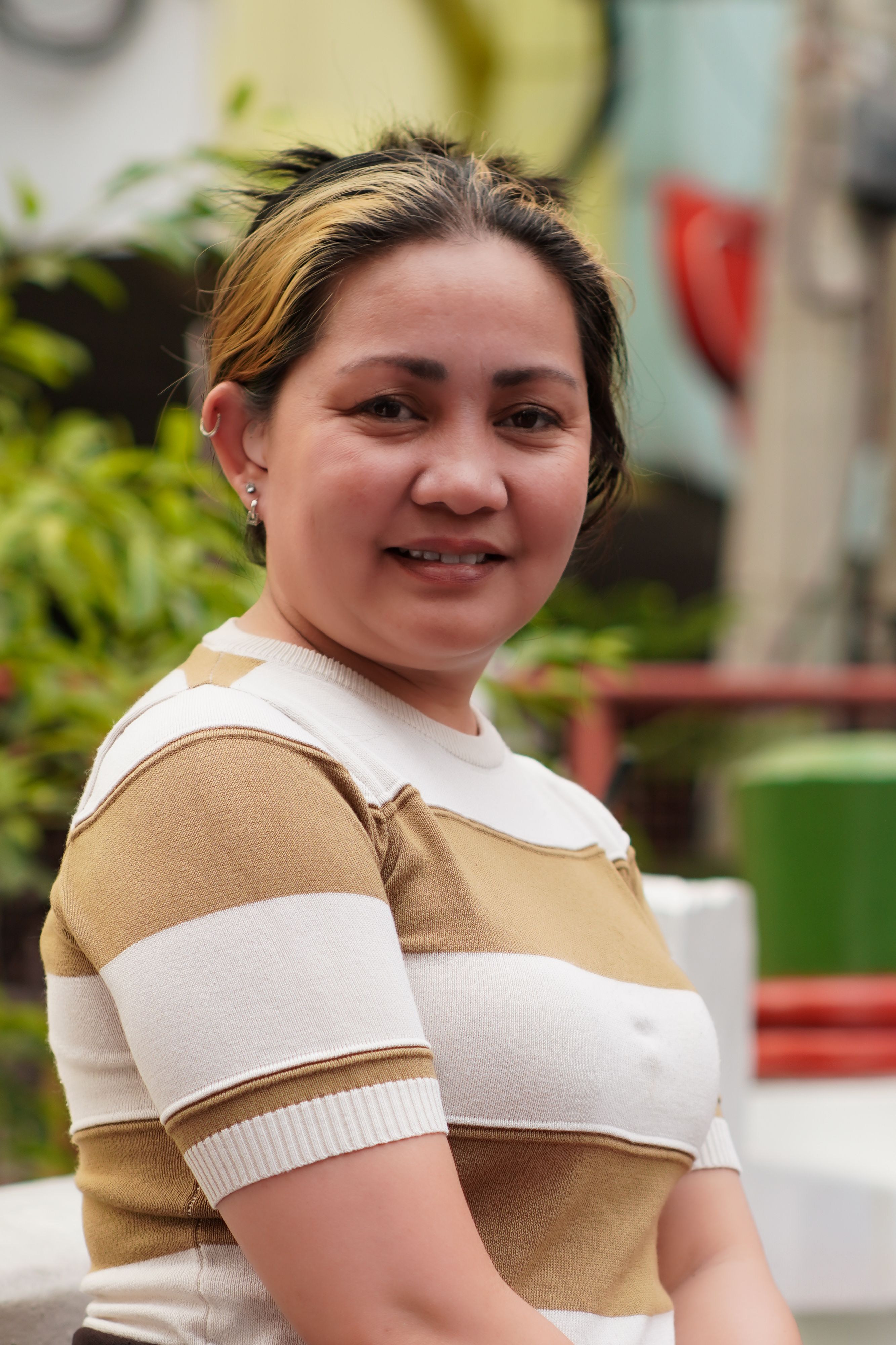 Smiling woman in striped shirt enjoying a sunny day outdoors.
