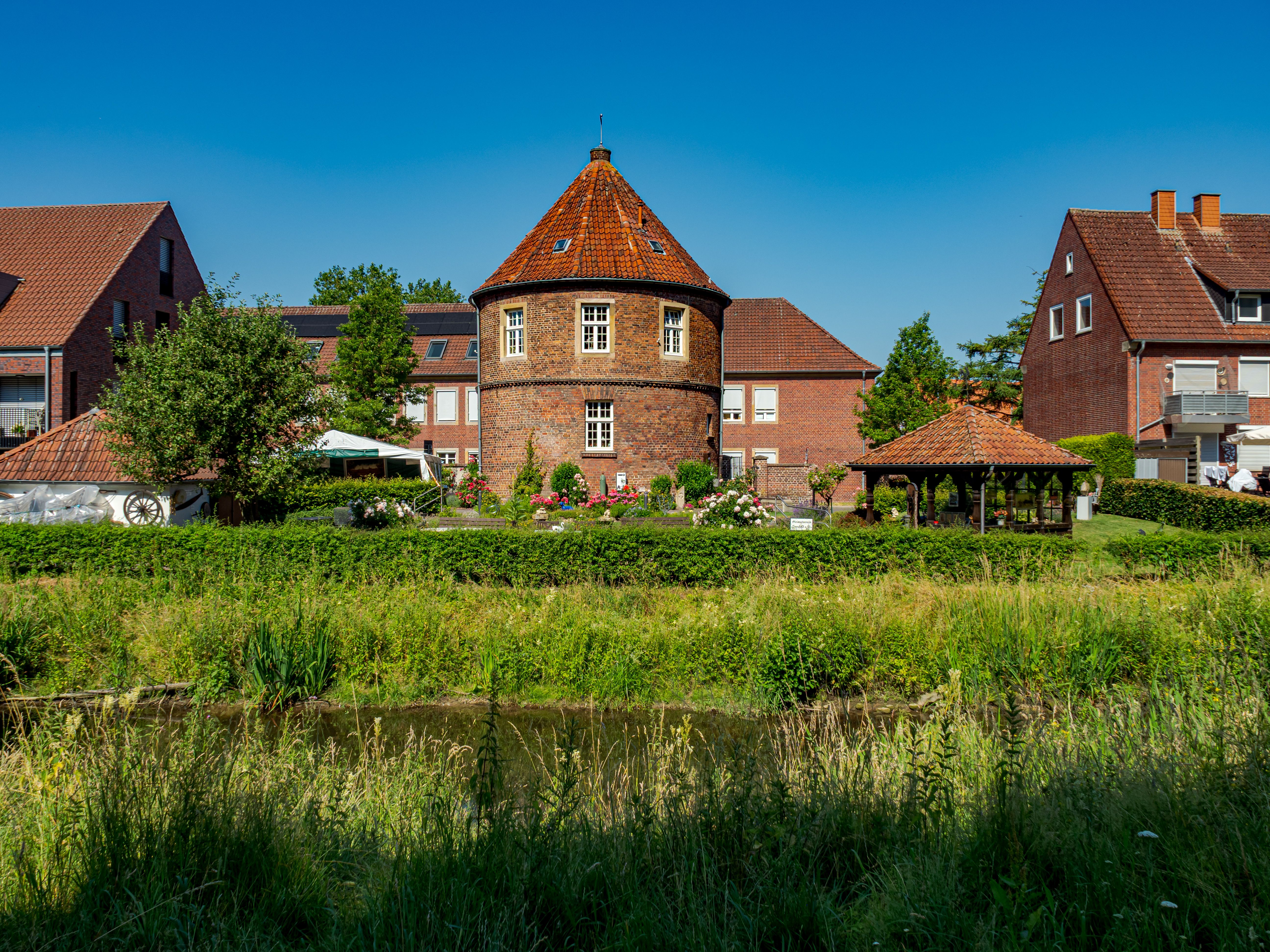 Historic roundhouse surrounded by lush greenery in Coesfeld, a picturesque village setting on a sunny day.
