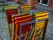 Brightly colored outdoor chairs stacked neatly in a brick-paved courtyard in Coesfeld, Germany.