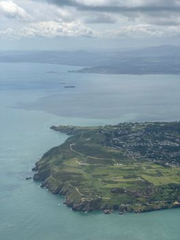 Stunning aerial view of Howth Peninsula coastline with green cliffs and ocean in Ireland.