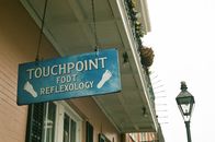 From below of signage with touchpoint foot reflexology text hanging on chains on ceiling of residential building near entrance