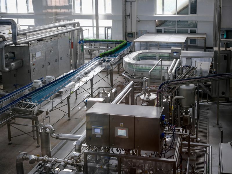 Interior view of an automated beverage bottling factory with machinery and conveyor belts