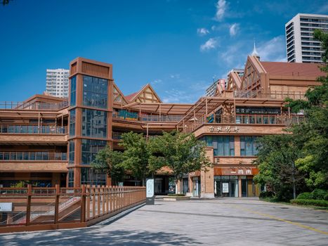 A contemporary wooden building with trees and a clear blue sky in an urban environment.