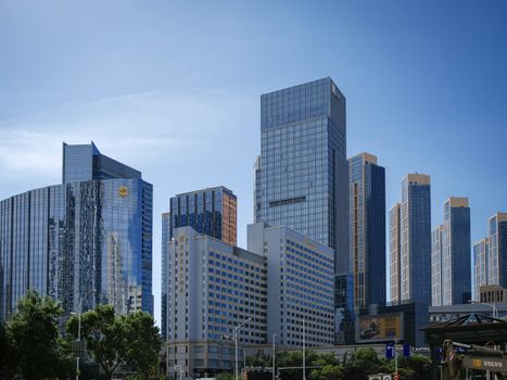 Urban skyline featuring modern skyscrapers with glass facades under a clear blue sky.