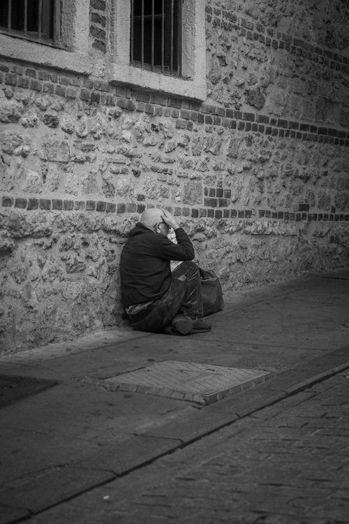Free Black and white photo of a man sitting on a street in Istanbul, highlighting urban solitude. Stock Photo