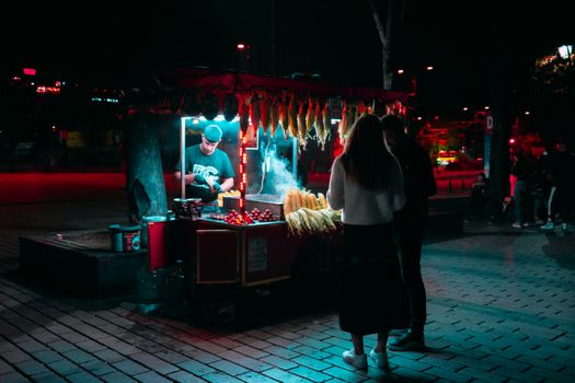 Nighttime street food vendor in Istanbul serving locals with corn and chestnuts.