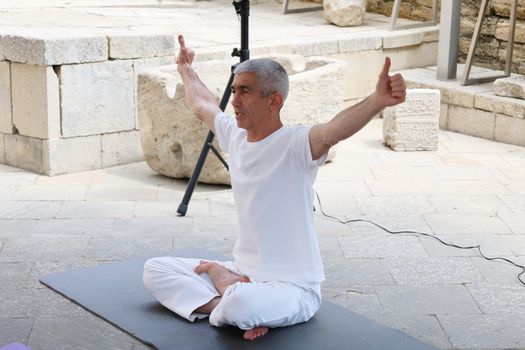 A senior man meditating in a yoga pose outdoors, expressing tranquility and balance.