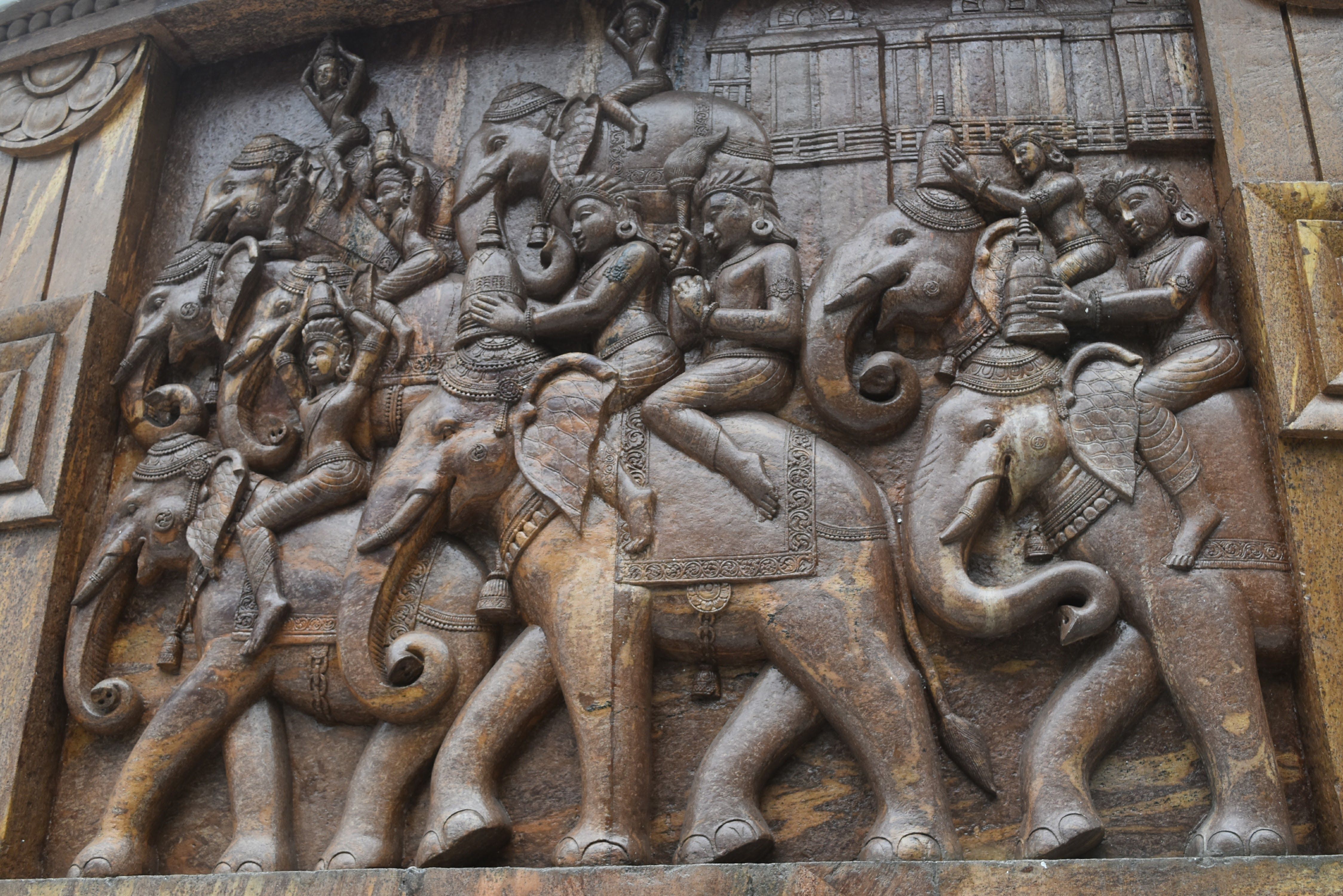 Ancient Indian relief depicting fighting roosters beside a temple courtyard at sunrise