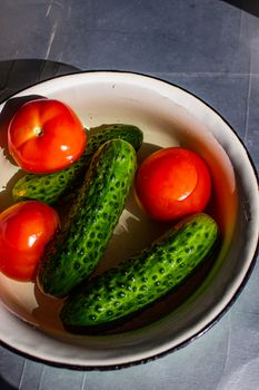 Vibrant tomatoes and cucumbers in a rustic bowl with natural lighting.