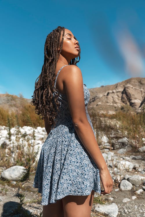 Woman in Gray and White Spaghetti Strap Dress Standing on Rocky Ground