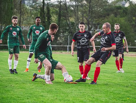 Dynamic football scene with players in action on a green pitch in France.