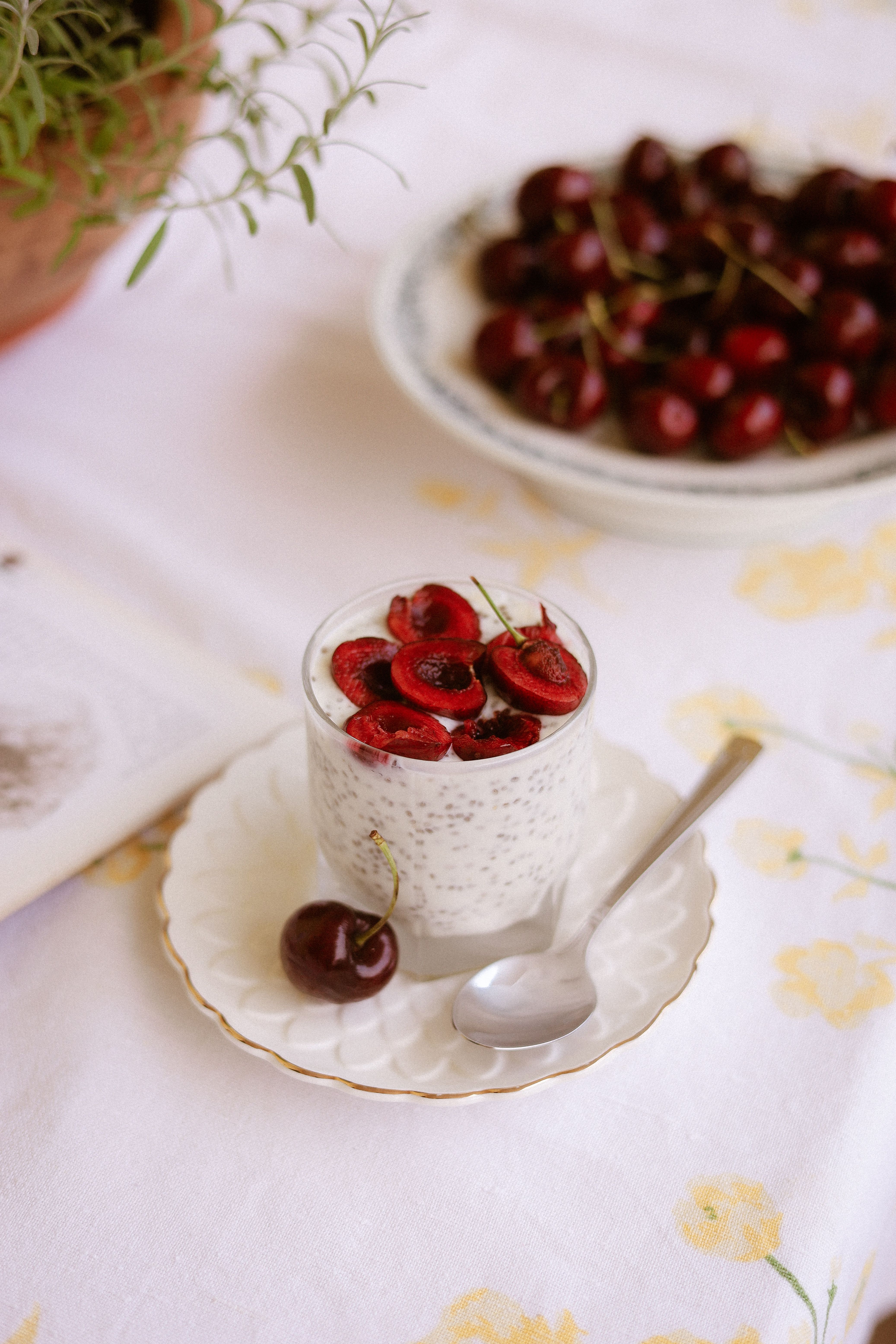 A tall glass of purple-pink chia seed smoothie topped with a sprinkle of whole chia seeds and fresh berries, with a stainless steel straw, next to a small bowl of dry chia seeds.