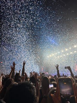 A lively concert scene in Amsterdam with confetti raining down on an enthusiastic crowd capturing the moment.