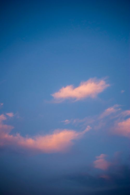 Free A tranquil sky at dusk with soft pink clouds against a blue backdrop. Stock Photo