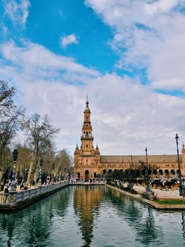 Beautiful view of Plaza de España in Seville, Spain, showcasing its architectural beauty and reflecting pond under a blue sky.