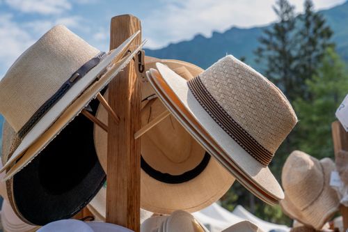 Free A collection of straw hats showcased on a wooden stand with scenic mountain backdrop. Stock Photo