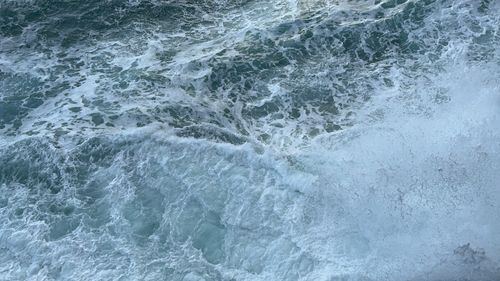 Free Aerial view of turbulent ocean waves crashing against the shore, showcasing nature's power. Stock Photo