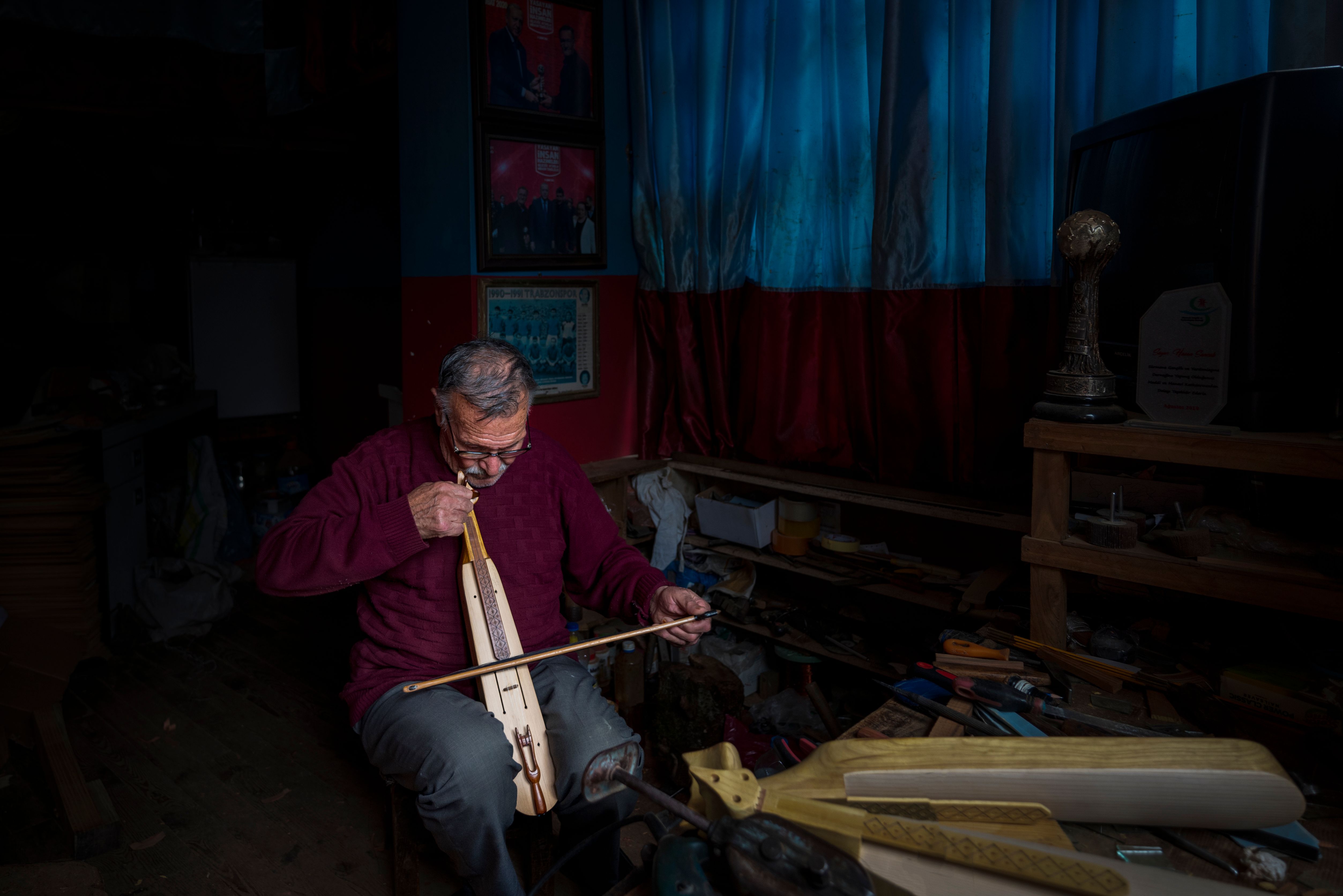 An elderly man playing a traditional bowed string instrument indoors in Sürmene, Türkiye.