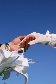 Gently holding hands under a clear sky, symbolizing marriage and unity.