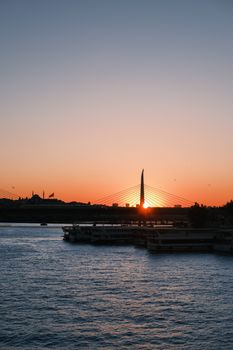 Beautiful sunset view over the Istanbul bridge with silhouettes and calm waters.