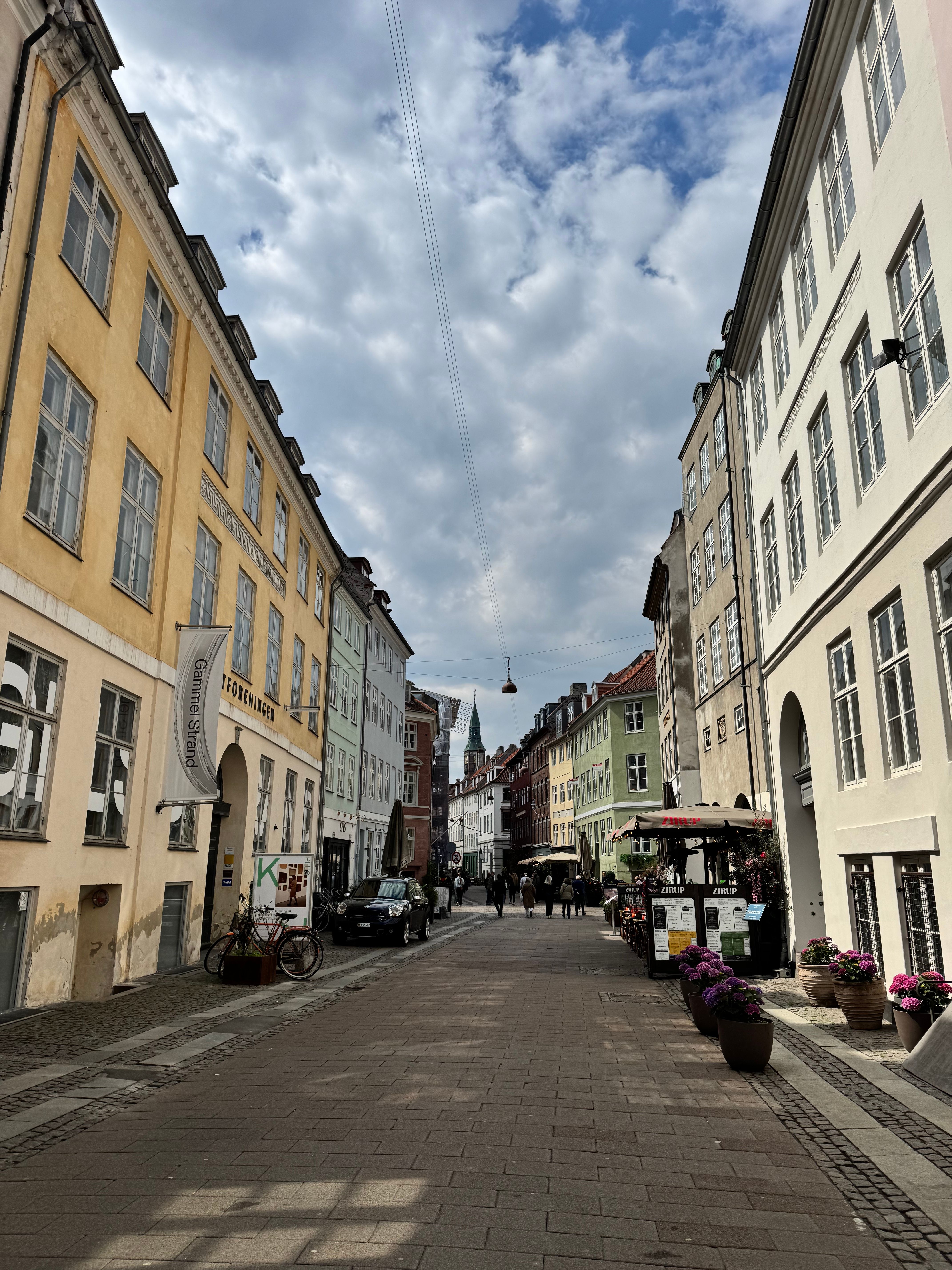 Charming Copenhagen street with colorful buildings under a cloudy sky.