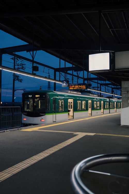 Free A serene twilight captures a train at a Japanese platform, showcasing urban tranquility. Stock Photo