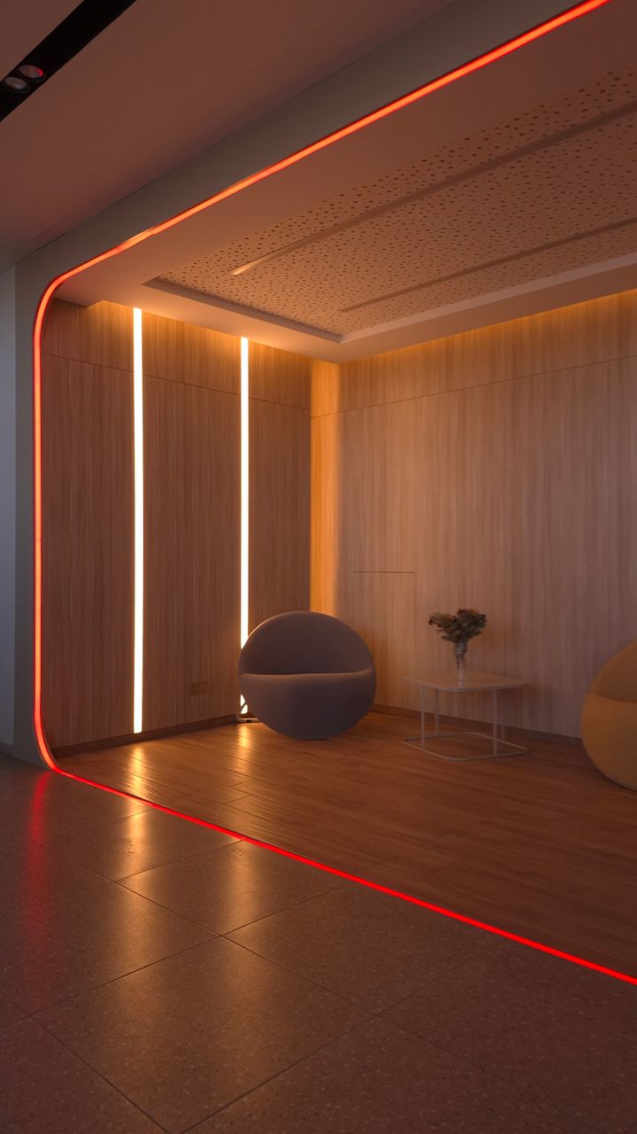 Warm LED strip lights mounted under a coffee bar shelf illuminating mugs and decor