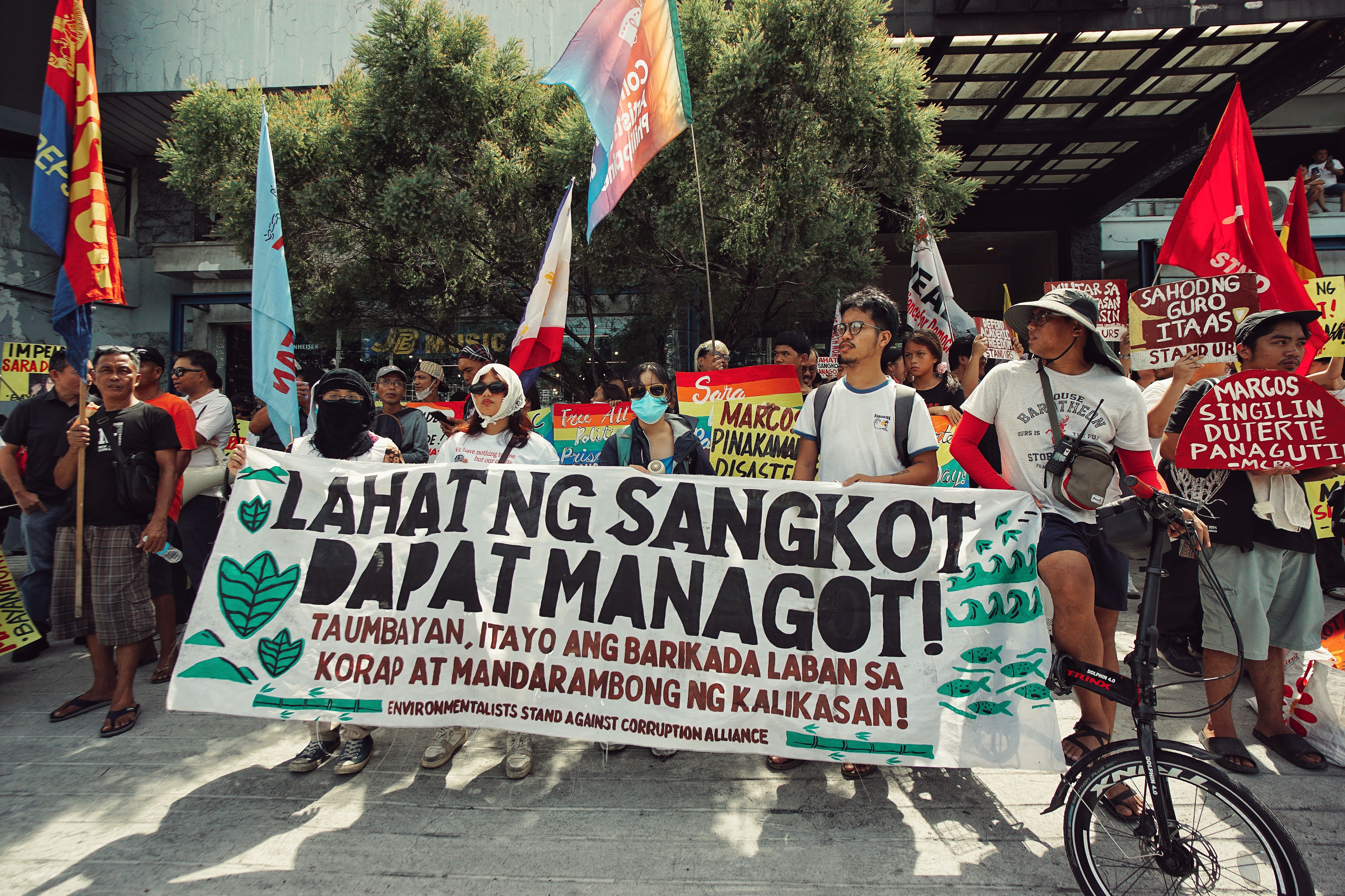 People in the Philippines protesting against corruption with banners and flags.