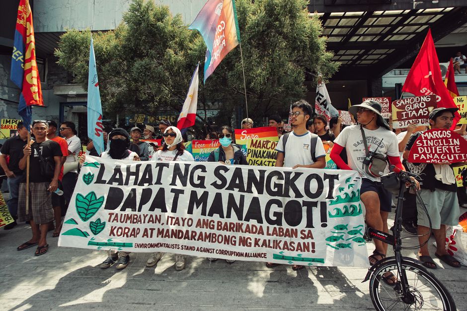 People in the Philippines protesting against corruption with banners and flags.