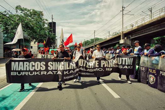 Protesters march with banners against capitalism on a city street.