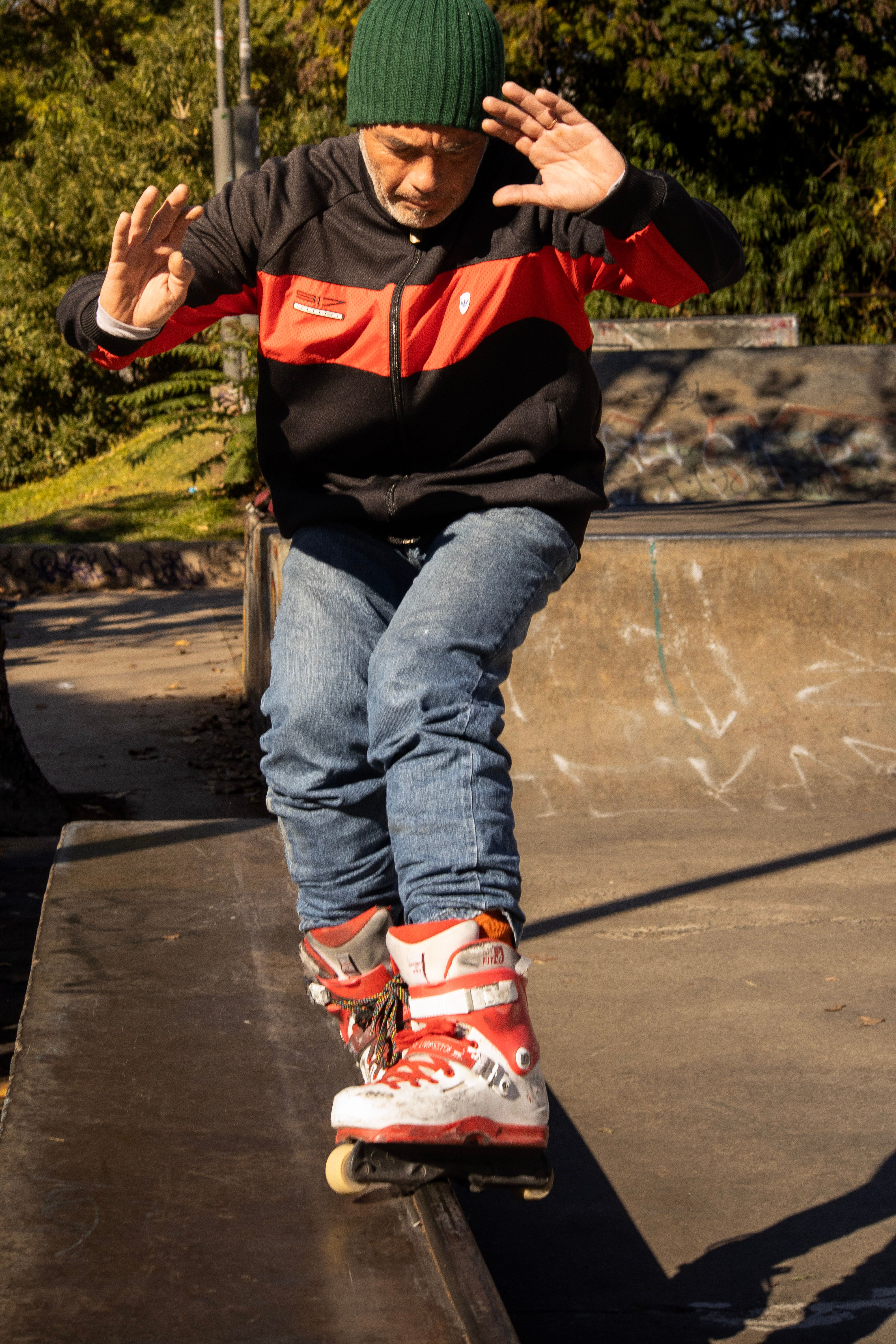 A person in a green beanie performs a skateboarding trick on a rail at an outdoor skate park.