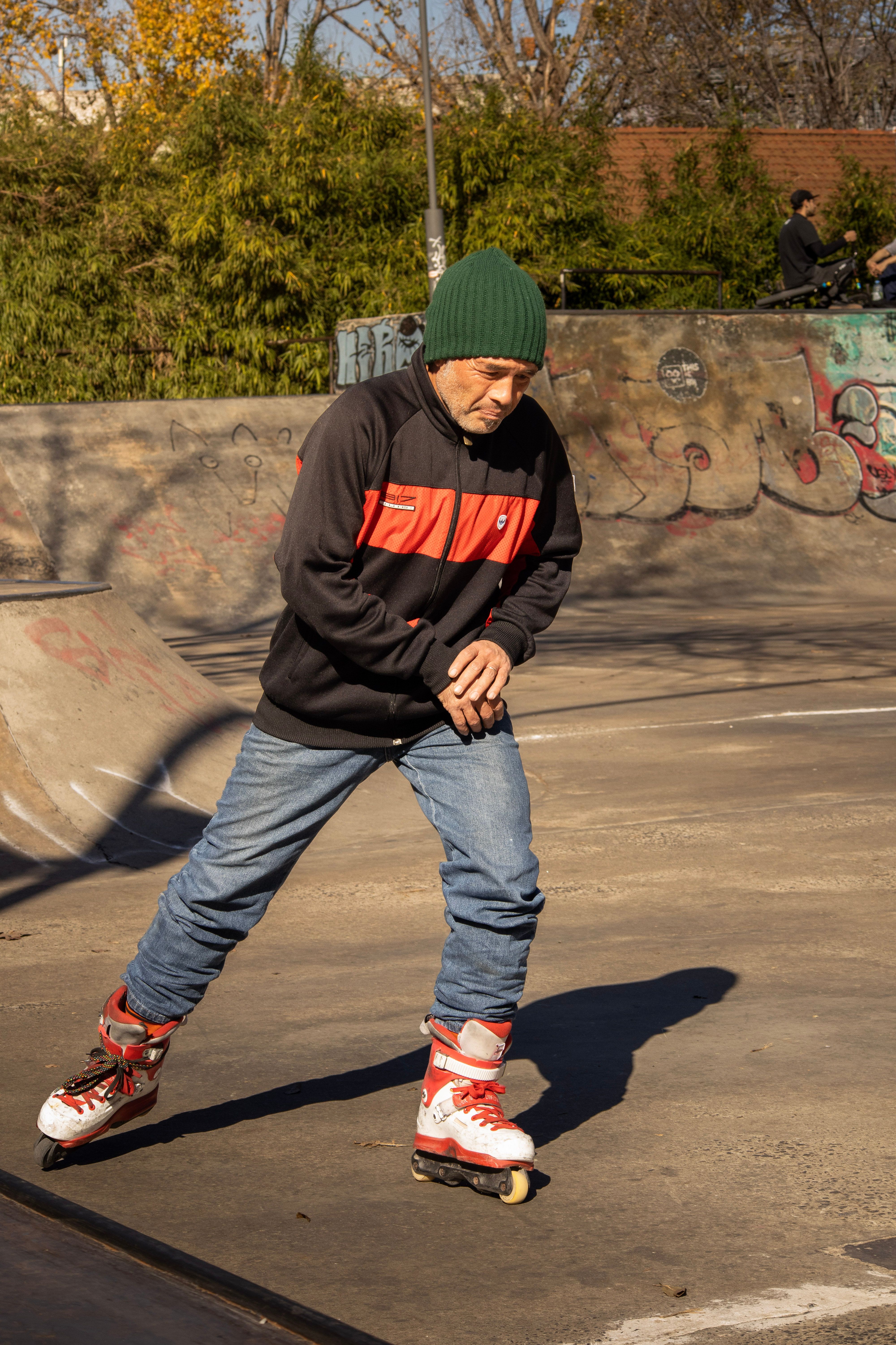 An active senior rollerblading confidently in a graffiti-covered urban skate park on a sunny day.