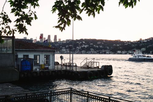 Free Charming sunset view of a pier on the Bosphorus with a boat and city skyline, capturing Istanbul's beauty. Stock Photo