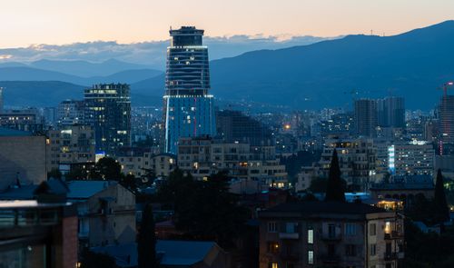 Free Twilight view of Tbilisi's skyline highlighting a distinctive modern skyscraper against mountain backdrop. Stock Photo