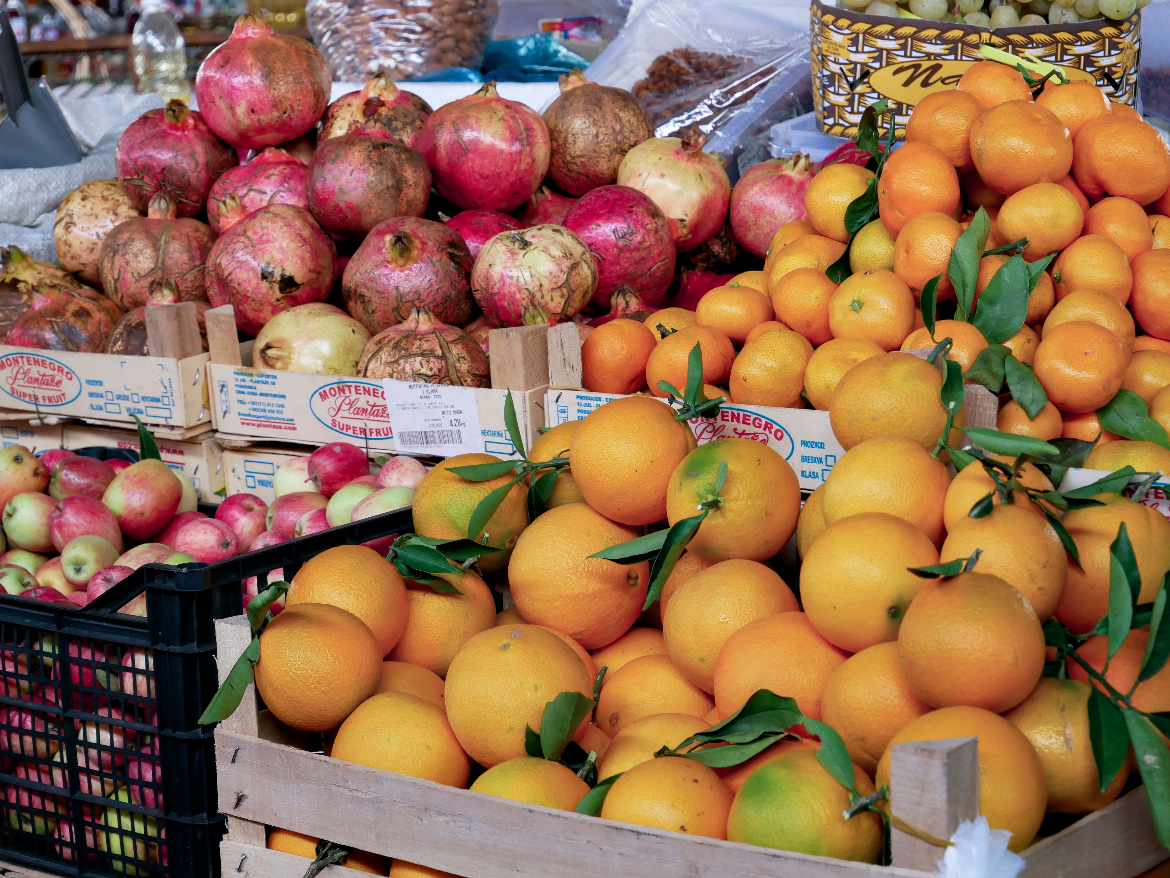 Feira de frutas com destaque para laranjas e romãs, ilustrando a variedade e frescor dos alimentos naturais.