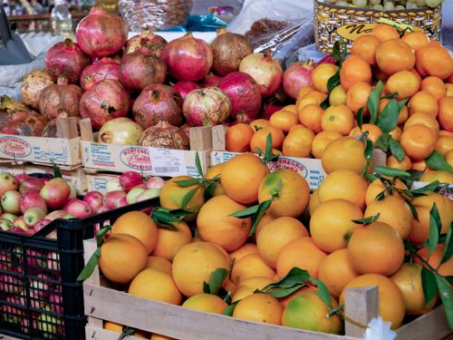 Free Vibrant oranges, pomegranates, and apples on display at a bustling local market. Stock Photo