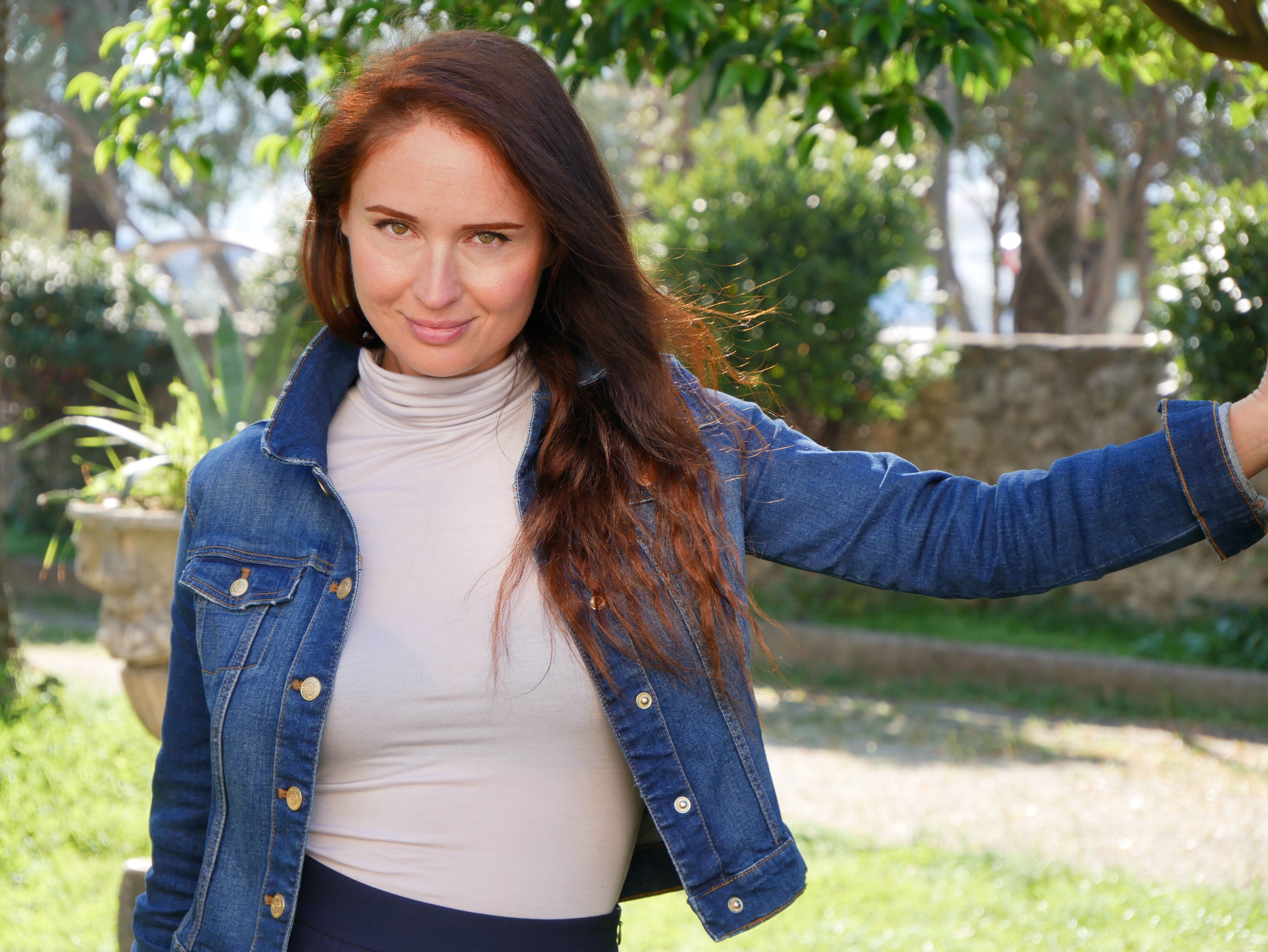 Casual portrait of a woman enjoying a sunny day in a garden setting.