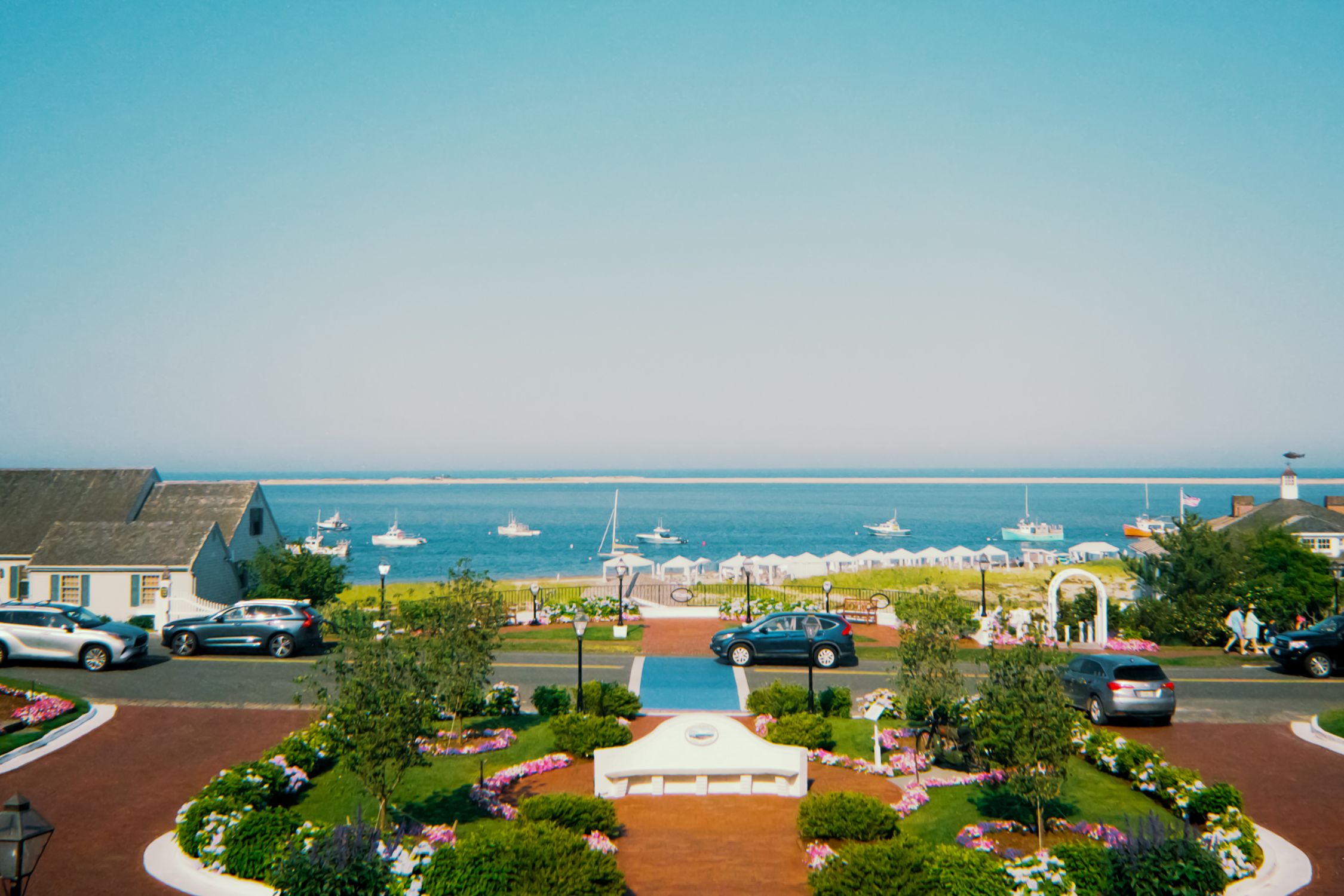 Beautiful summer view of Chatham Harbor with boats and lush gardens, perfect for travel and leisure imagery.