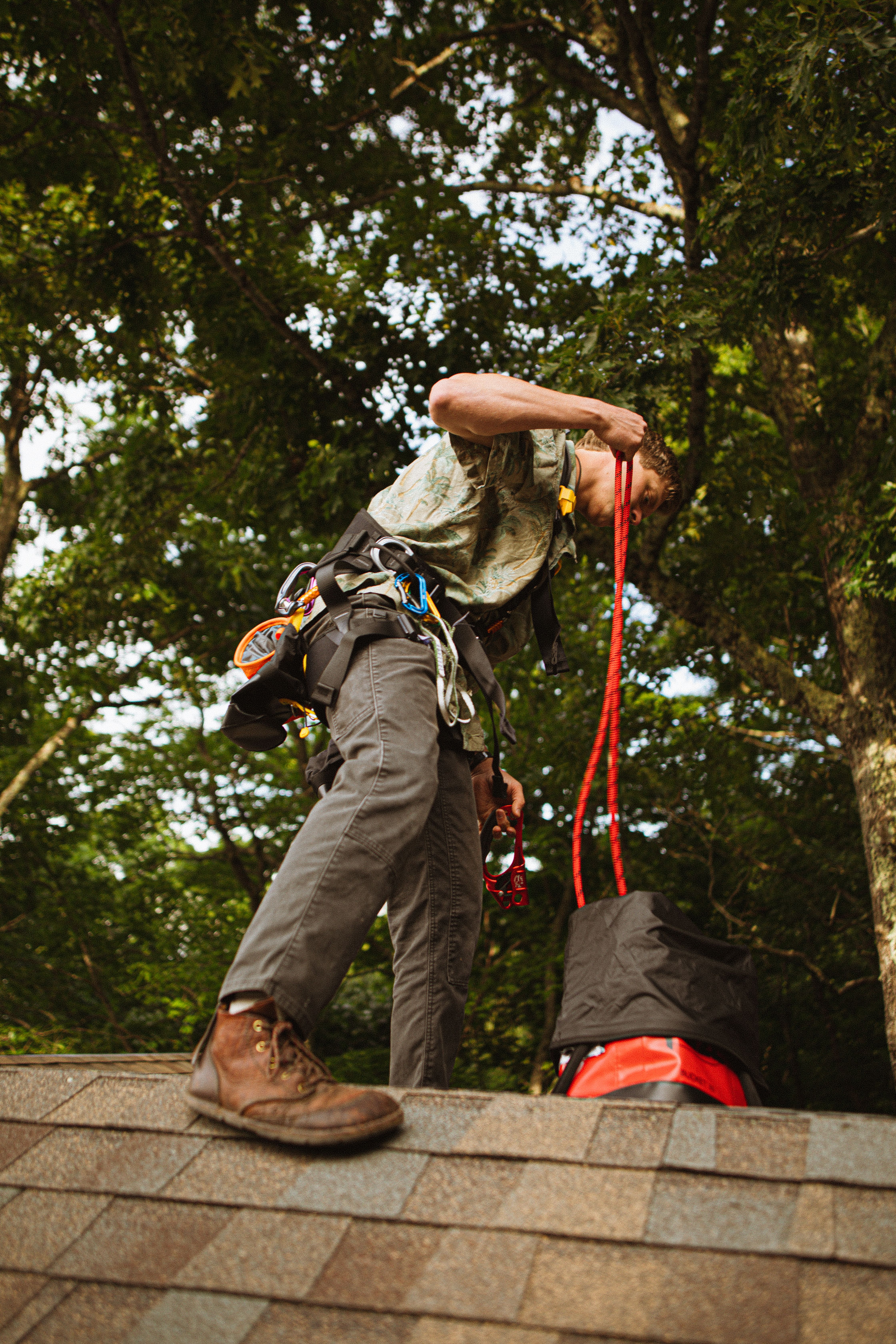 Construction worker on a roof with safety gear in lush North Carolina setting.