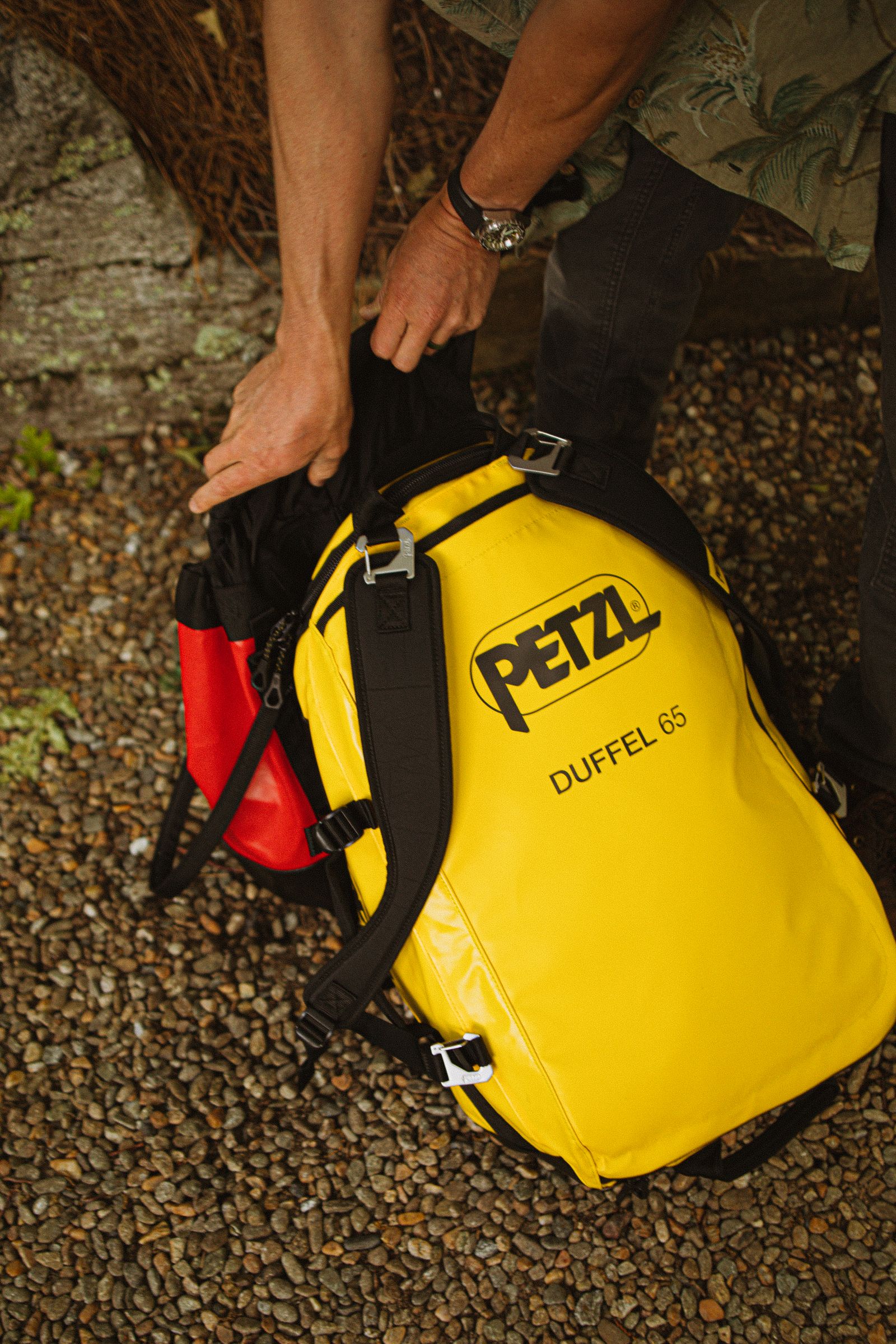 Person packing a duffel bag with outdoor gear for travel